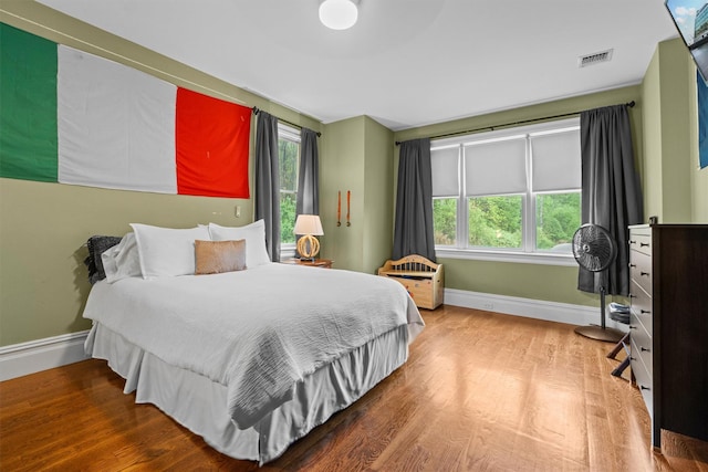 bedroom with baseboards, multiple windows, and wood finished floors
