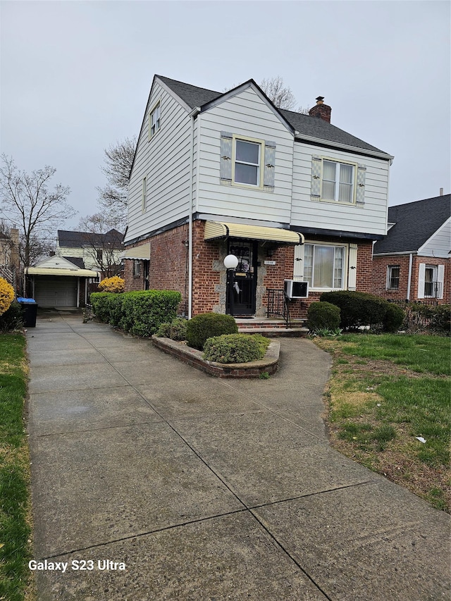 11568 229th St, Cambria Heights, NY 11411 - view of front of house with brick siding, a chimney, an outdoor structure, a detached garage, and driveway