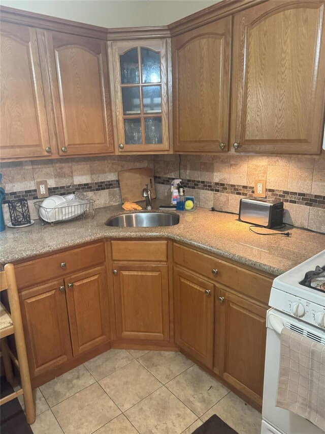 11568 229th St, Cambria Heights, NY 11411 - kitchen featuring a sink, tasteful backsplash, gas range gas stove, light tile patterned floors, and glass insert cabinets