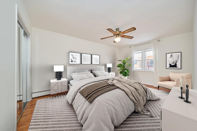 6629 74th St, Middle Village, NY 11379 - bedroom with baseboard heating, wood finished floors, and a ceiling fan