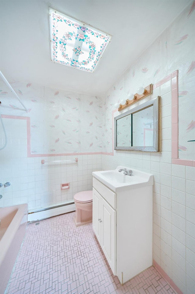 6629 74th St, Middle Village, NY 11379 - bathroom featuring tile walls, baseboard heating, toilet, vanity, and wallpapered walls