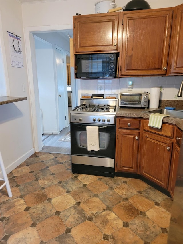 53 Bayview Ave, East Islip, NY 11730 - kitchen featuring gas range oven, black microwave, decorative backsplash, and brown cabinets