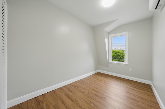234 Quincy Ave, Bronx, NY 10465 - empty room featuring baseboards, a wall mounted AC, wood finished floors, and vaulted ceiling