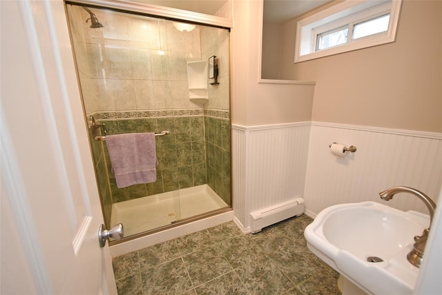bathroom featuring baseboard heating, a stall shower, and wainscoting
