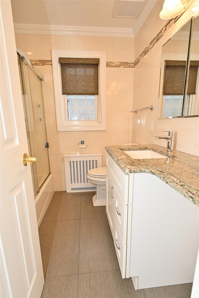full bath featuring radiator, tile walls, toilet, ornamental molding, and shower / bath combination with glass door