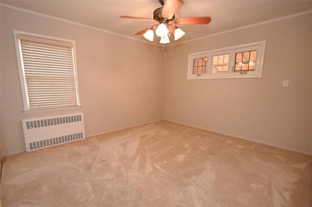 empty room with radiator, ornamental molding, carpet, a ceiling fan, and baseboards