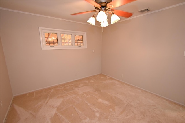 empty room with light colored carpet, crown molding, a ceiling fan, and baseboards