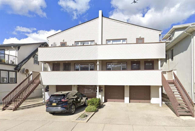 view of front of home with stairs, an attached garage, and driveway