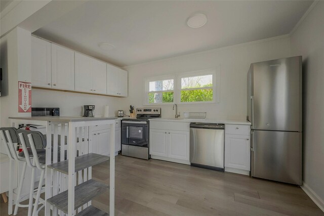 28 Lynncliff Rd, Hampton Bays, NY 11946 - kitchen featuring stainless steel appliances, a sink, white cabinetry, light countertops, and light wood-style flooring