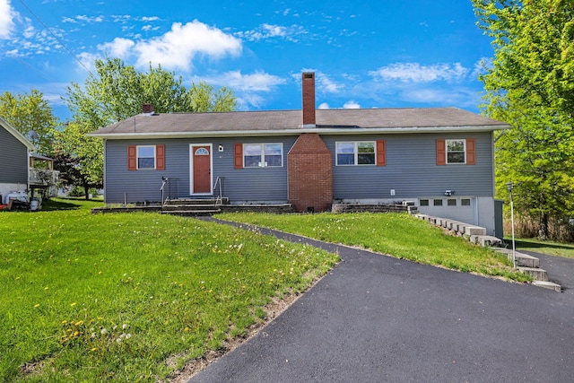 single story home with entry steps, an attached garage, a chimney, and a front lawn