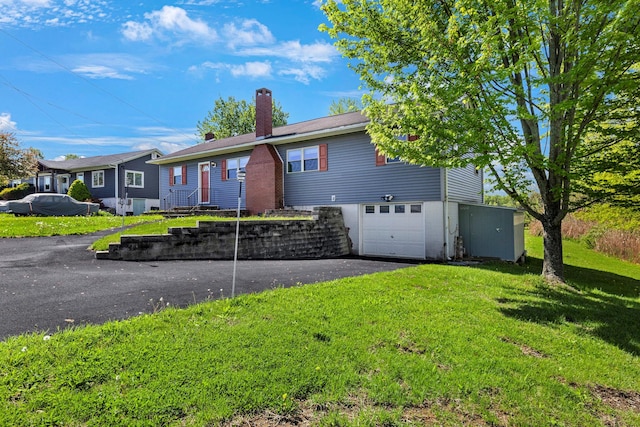 ranch-style home featuring a garage, a chimney, a front yard, and driveway