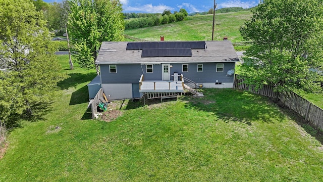 rear view of house with a deck and roof mounted solar panels