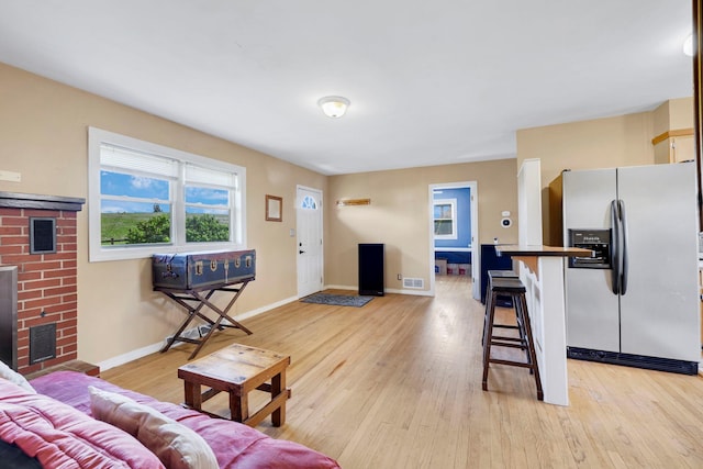 living room with light wood-style flooring, a fireplace, and baseboards