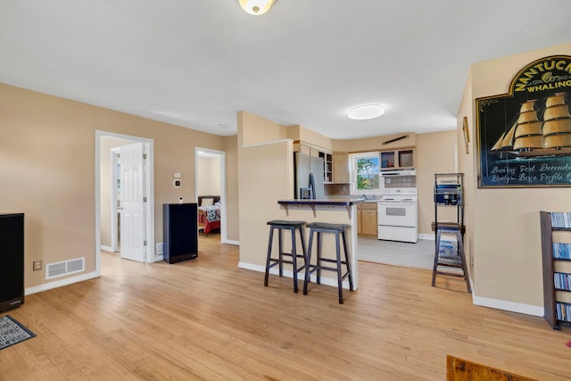 kitchen with white electric stove, stainless steel refrigerator with ice dispenser, a breakfast bar, a peninsula, and open shelves