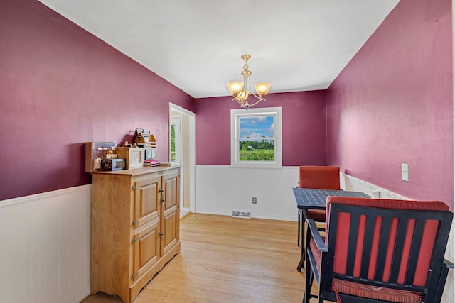 dining space featuring a chandelier, wainscoting, and light wood finished floors