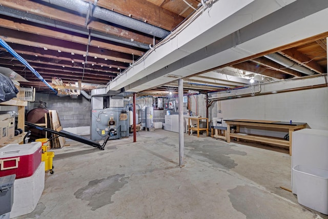 unfinished basement featuring electric water heater, heating unit, and concrete block wall