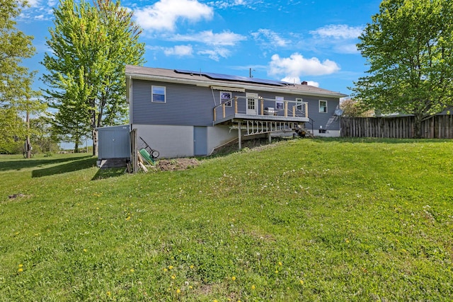 rear view of property featuring a deck and roof mounted solar panels