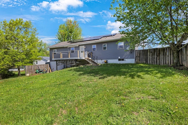 rear view of house with solar panels, a deck, and stairway