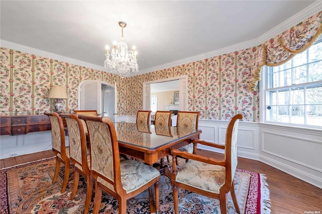 3 Barkers Point Rd, Sands Point, NY 11050 - dining space featuring wood-type flooring, a chandelier, arched walkways, wallpapered walls, and ornamental molding