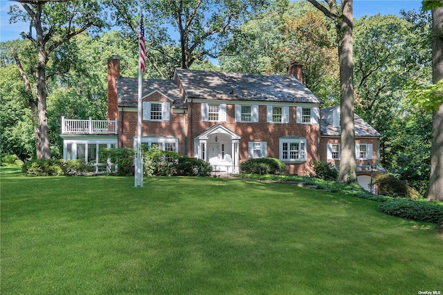 3 Barkers Point Rd, Sands Point, NY 11050 - colonial inspired home with a chimney, a front yard, a balcony, and brick siding