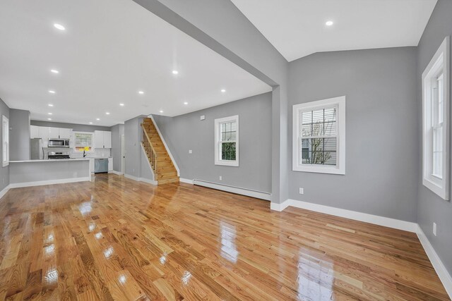 11827 219th St, Cambria Heights, NY 11411 - unfurnished living room with baseboard heating, light wood-style flooring, baseboards, recessed lighting, and stairs