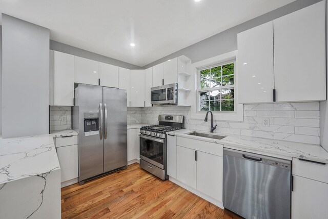 11827 219th St, Cambria Heights, NY 11411 - kitchen featuring appliances with stainless steel finishes, a sink, open shelves, white cabinetry, and light wood-style floors