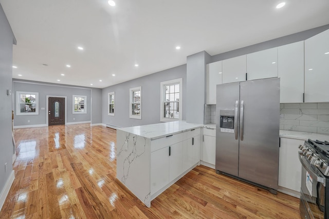 11827 219th St, Cambria Heights, NY 11411 - kitchen featuring stainless steel refrigerator with ice dispenser, range with gas stovetop, a peninsula, backsplash, and white cabinetry