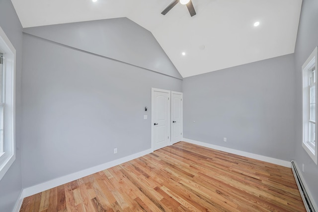 11827 219th St, Cambria Heights, NY 11411 - empty room featuring a baseboard heating unit, ceiling fan, high vaulted ceiling, wood finished floors, and baseboards