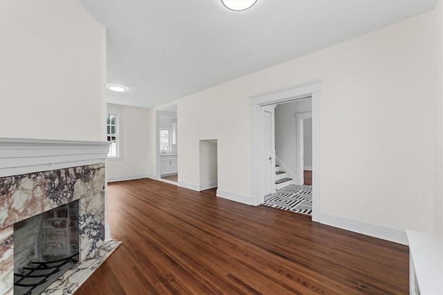 unfurnished living room with wood finished floors, a tiled fireplace, baseboards, and a sink