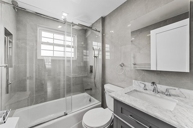 full bathroom with toilet, vanity, enclosed tub / shower combo, and tile walls