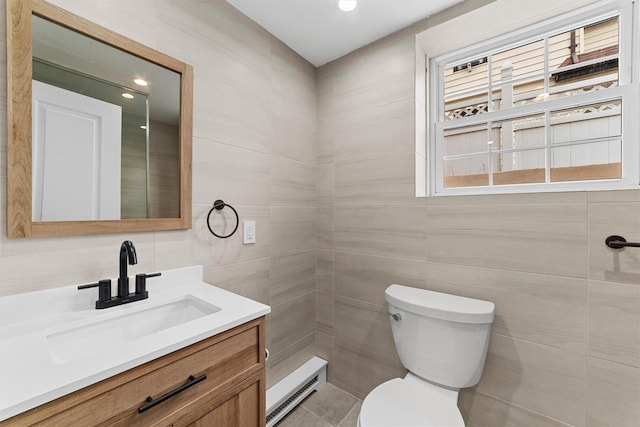 bathroom featuring tile walls, toilet, baseboard heating, vanity, and recessed lighting