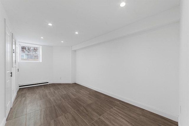 basement featuring a baseboard heating unit, recessed lighting, and baseboards