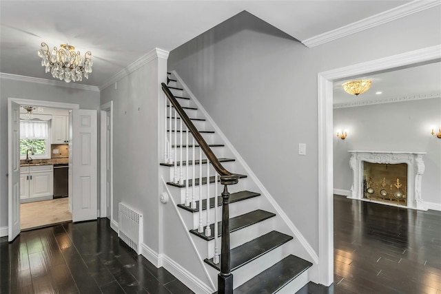 8 Hazel Rd, Port Washington, NY 11050 - staircase featuring wood finished floors, crown molding, a chandelier, and a fireplace