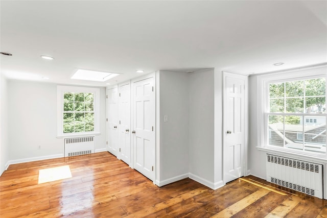 8 Hazel Rd, Port Washington, NY 11050 - unfurnished bedroom featuring radiator heating unit, multiple closets, hardwood / wood-style floors, and recessed lighting