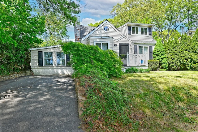 view of front of house featuring a chimney, a front yard, and asphalt driveway