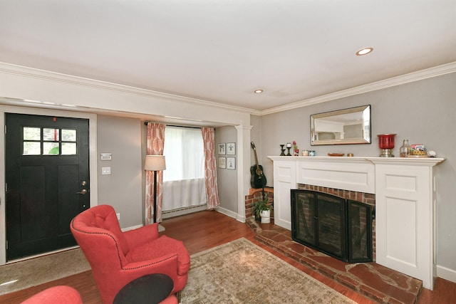 living area with baseboard heating, ornamental molding, baseboards, a fireplace, and wood finished floors
