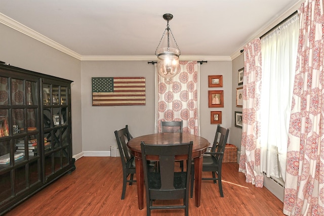 dining space featuring wood finished floors, crown molding, and baseboards