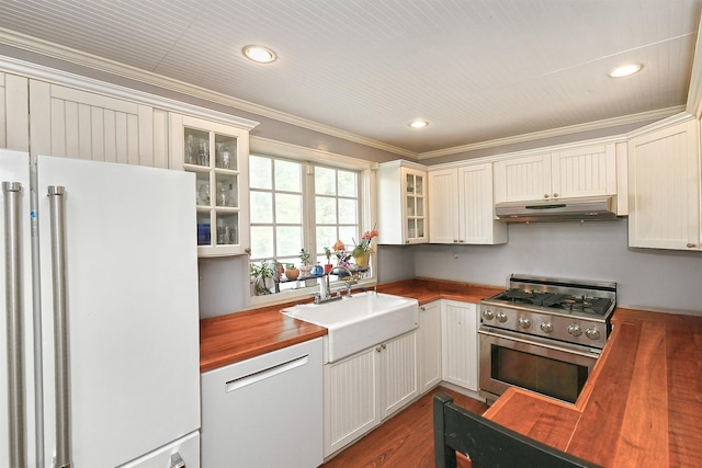 kitchen with wood counters, high end range, freestanding refrigerator, under cabinet range hood, and a sink