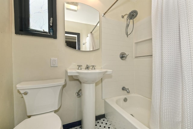 bathroom with toilet, shower / bath combo with shower curtain, and a sink