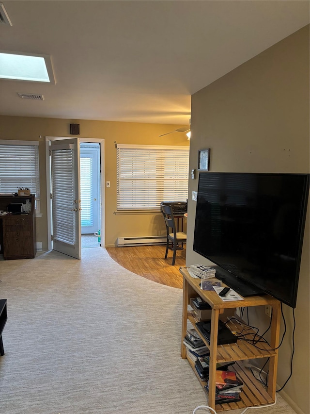 living area with a ceiling fan and a baseboard heating unit