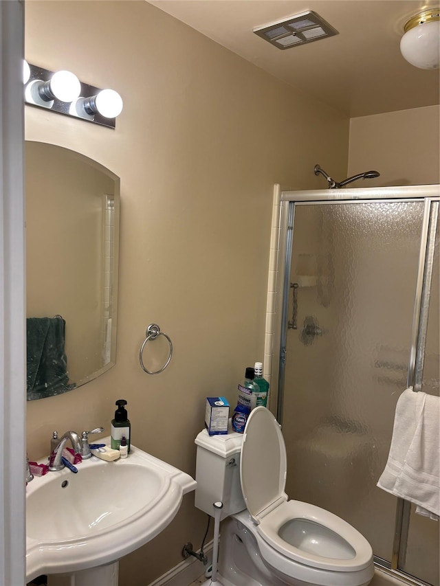 bathroom featuring a sink, a shower stall, toilet, and baseboards