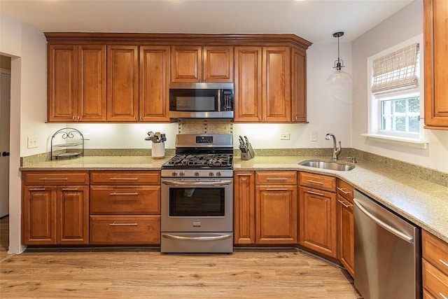 50 Louisiana Ave Unit 9R, Bronxville, NY 10708 - kitchen featuring stainless steel appliances, a sink, brown cabinetry, light wood-style floors, and hanging light fixtures