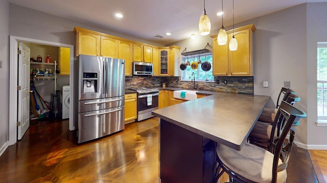 293 S Centerville Rd, Middletown, NY 10940 - kitchen featuring stainless steel appliances, a peninsula, washer / clothes dryer, decorative backsplash, and plenty of natural light