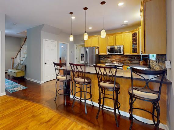 293 S Centerville Rd, Middletown, NY 10940 - kitchen featuring stainless steel appliances, a peninsula, wood finished floors, tasteful backsplash, and baseboards