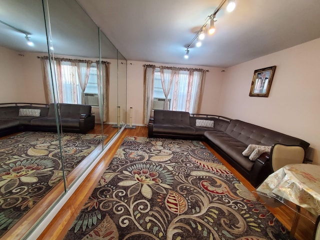 living room with rail lighting, wood finished floors, and cooling unit