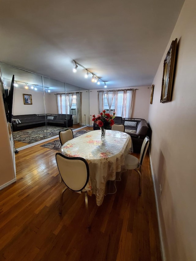 dining space with wood finished floors, track lighting, and baseboards