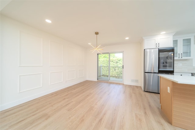 2001 Wellington Ct, Westbury, NY 11590 - kitchen with freestanding refrigerator, light wood-style floors, light countertops, a chandelier, and white cabinetry