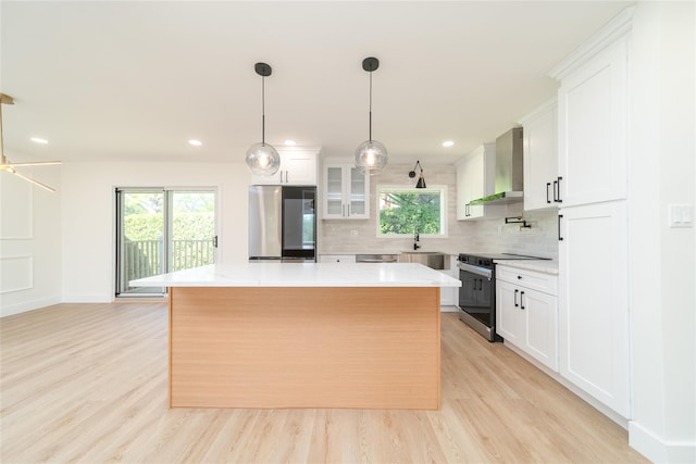 2001 Wellington Ct, Westbury, NY 11590 - kitchen with stainless steel appliances, wall chimney range hood, a center island, decorative backsplash, and white cabinets