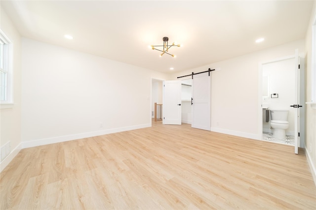 2001 Wellington Ct, Westbury, NY 11590 - unfurnished bedroom featuring a barn door, light wood-type flooring, baseboards, ensuite bathroom, and recessed lighting