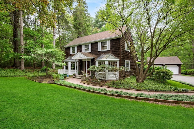 shingle-style home with a front lawn, a garage, a shingled roof, and driveway
